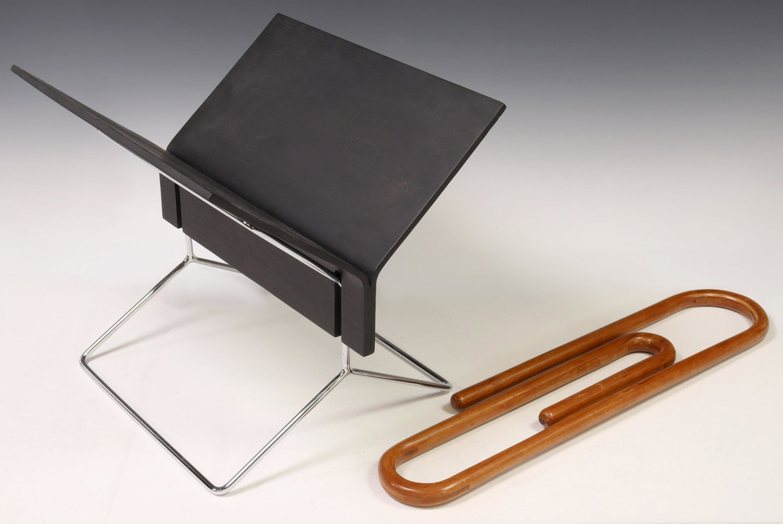 2) MODERN OFFICE ACCESSORIES SCULPTURE & BOOKSTAND: (lot of 2) Modern office accessories, including: (1) large sculptural bentwood paper clip, incised at end with artist mark(?) 20, approx 23.5"h, 5 3/8"w; (1) bookstand, black painted wood, on chromed 