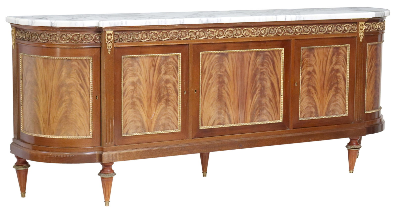 LOUIS XVI STYLE MARBLE-TOP MAHOGANY SIDEBOARD: French Louis XVI style marble-top sideboard, 20th c., flame mahogany case, with gilt metal rinceau border, over five cabinets, central left cabinet fitted with four drawers, rising on fluted and taper