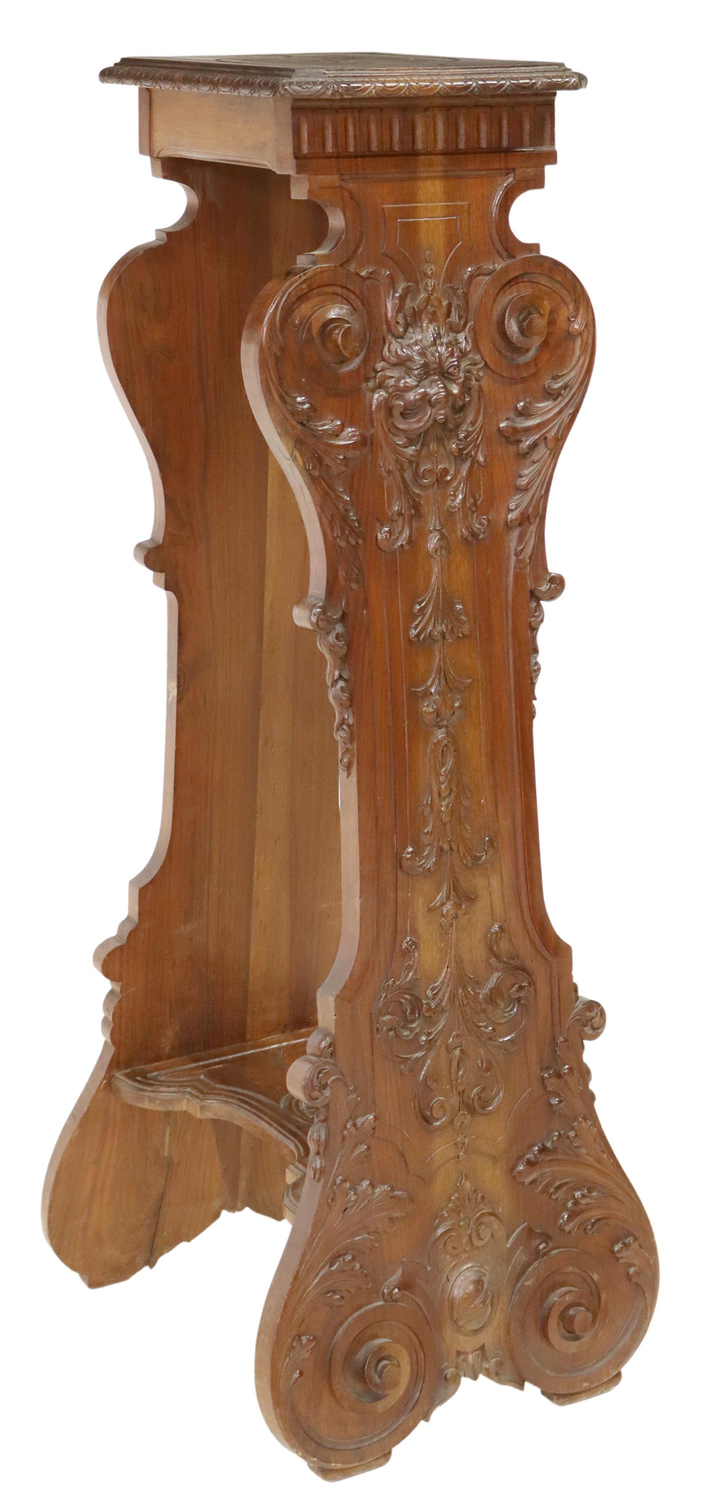 RENAISSANCE REVIVAL CARVED WALNUT HALL PEDESTAL: Renaissance Revival carved walnut pedestal, early 20th c., having lunette border top, over volute supports, one side carved with grotesque mask and foliates, joined with shaped center stretcher, risin