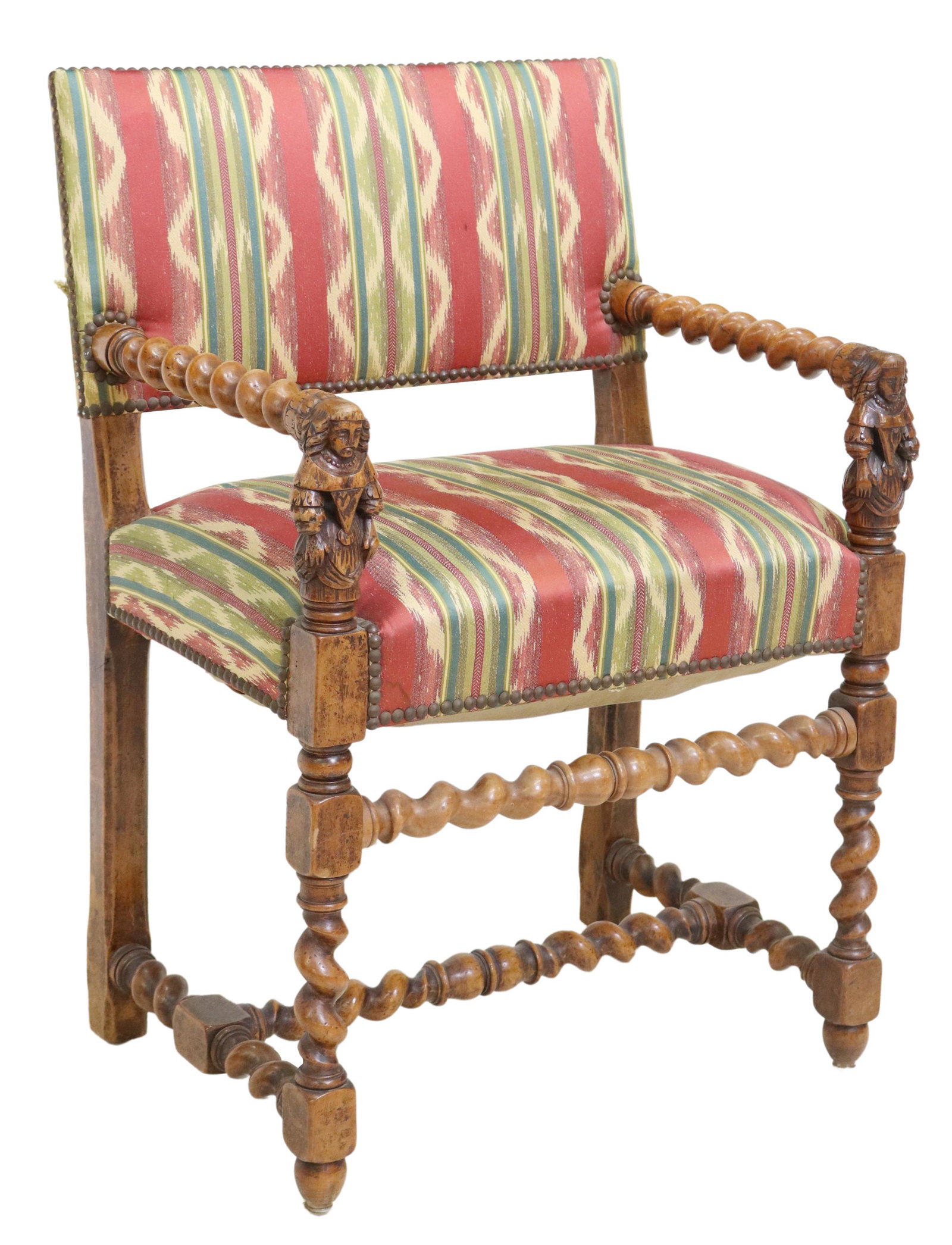 FRENCH LOUIS XIII STYLE CARVED WALNUT FAUTEUIL: French Louis XIII style carved walnut armchair, 19th c., back and seat in patterned upholstery, with nailhead trim, figural carved handholds, rising on stretcher-joined twist legs, ending on turned fe