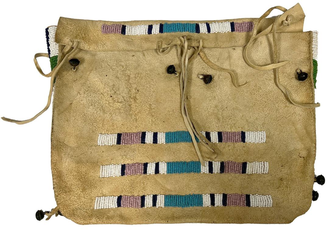 NATIVE AMERICAN CENTRAL PLAINS POSSIBLE BAG C1910: Central plains beaded possible bag, deer hide, c. 1900-1920, beaded accents at front, flap and sides, eight bells attached to the front and lower sides, approx. 12"h, 16"w Start Price: $150.00