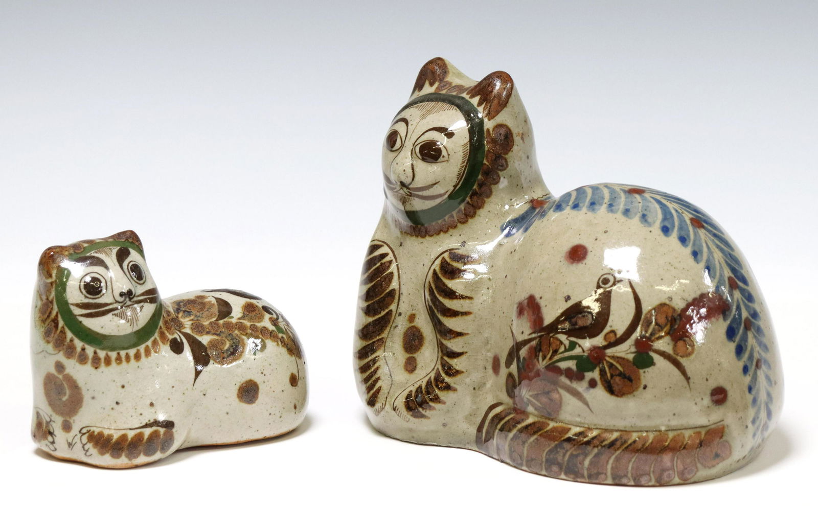 (2) JORGE WILMOT (D2012) TONALA FOLK ART POTTERY: (lot of 2) Mexican folk art pottery reclining cats, initialed W at side (Jorge Wilmot, Tonala, Mexico, 1928-2012), with hand painted birds and foliate motifs, largest: approx 6"h, 7"w, 5"d, 3.4lbs tot