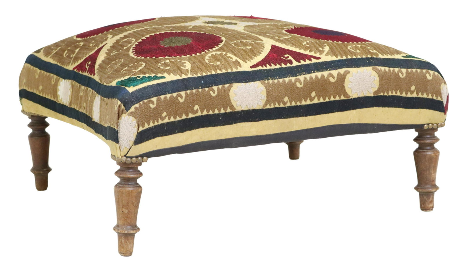 EMBROIDERED UPHOLSTERED OTTOMAN ON TURNED LEGS: Upholstered ottoman, embroidered upholstery, possibly a Suzani textile fragment, rising on turned wood legs, small tear and thread loss, approx 14.5"h, 28"w, 25"d Start Price: $150.00