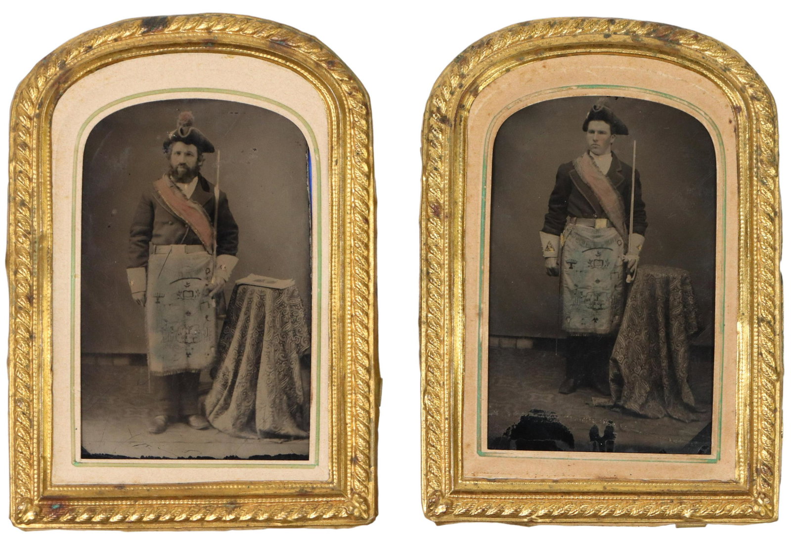 (2) MASONIC TINTYPES, 19TH C. HAND TINTED: (lot of 2) Masonic tintypes, 19th c., hand tinted, each depicting a man with Masonic regalia including a tricorn hat, sash and symboled apron attached to their belts, each photo with metal frame appro