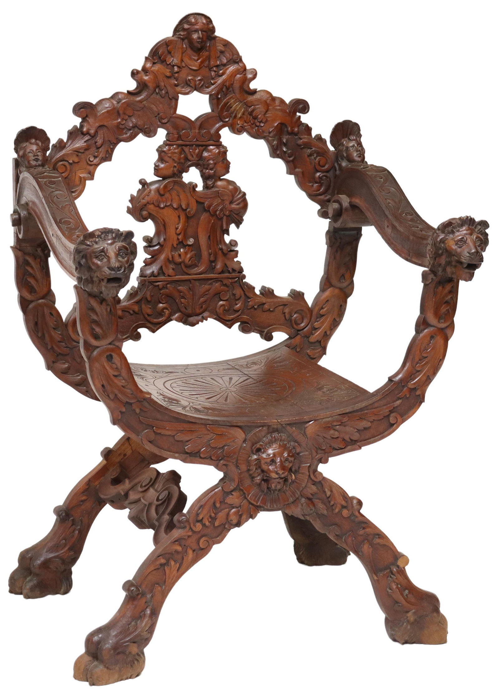 ITALIAN RENAISSANCE REVIVAL CARVED CURULE CHAIR: Italian Renaissance Revival carved walnut armchair, 19th c., carved mask crest, over splat with opposing winged figures, arms terminating in carved lion masks, incised seat, curule base joined by side