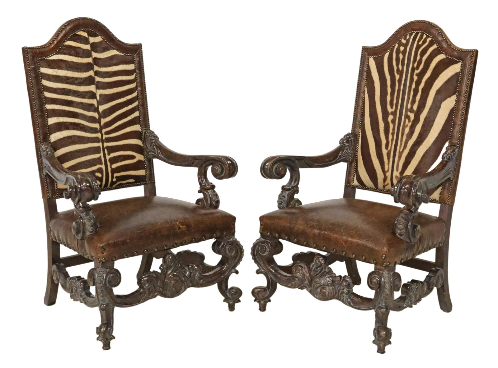(2) ITALIAN BAROQUE STYLE HIGHBACK ZEBRA ARMCHAIRS: (pair) Italian Baroque style highback armchairs, 20th c., having shaped back, in zebra hide and embossed leather upholstery, nailhead trim, scrolled armrests, rising on cabriole legs, joined by box st