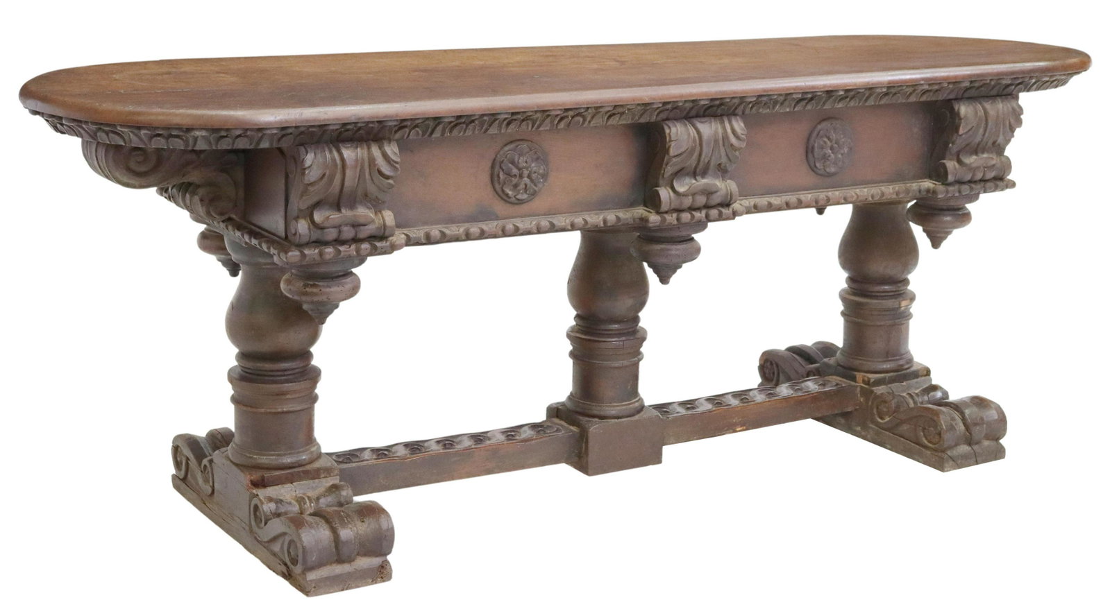 BAROQUE STYLE CARVED OAK TRESTLE LIBRARY TABLE: Baroque style carved oak library table, 19th c., having rounded top, fitted with two drawers, carved foliate border, over drop finials, rising on turned stretcher-joined supports, ending on large scro