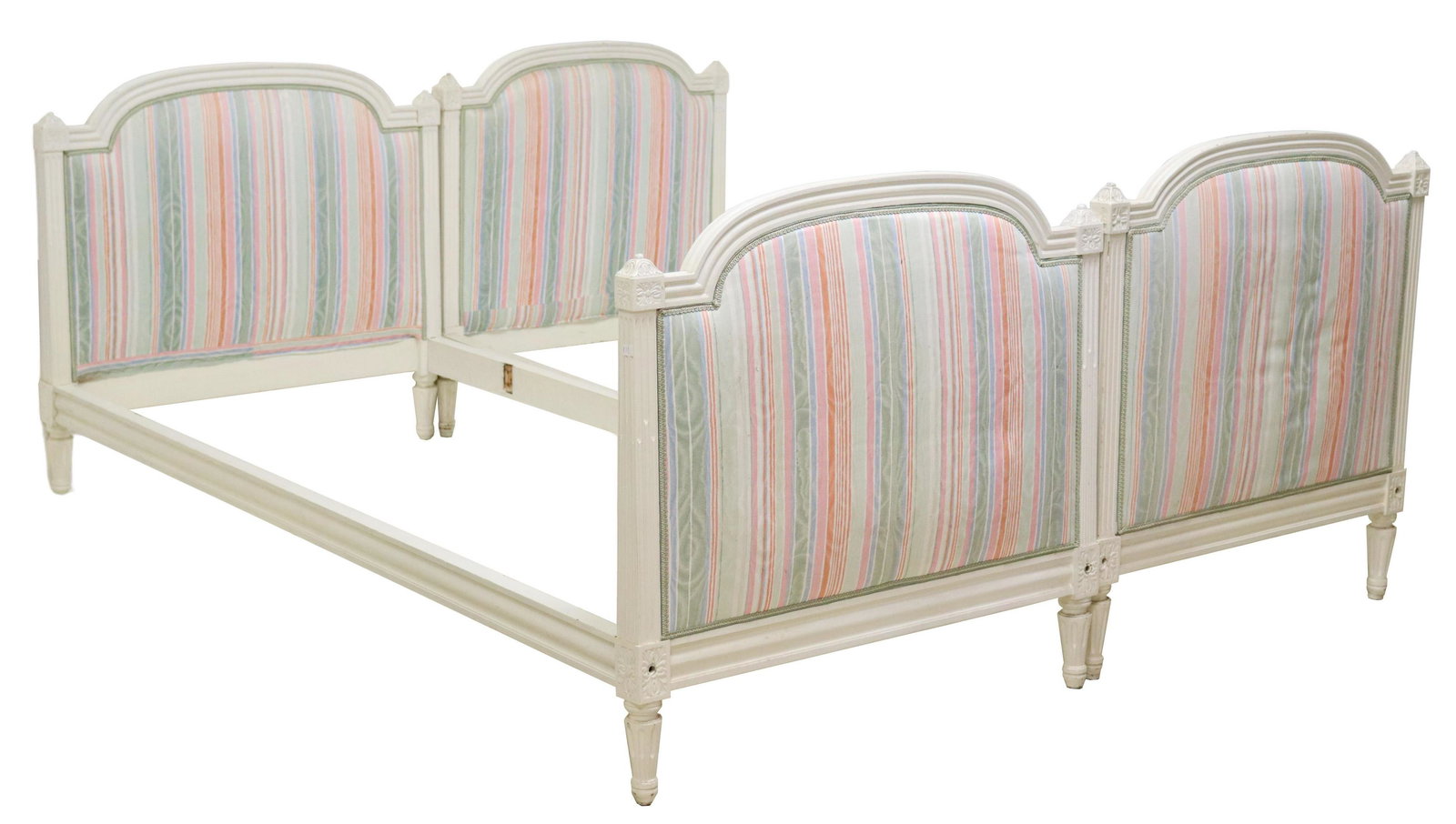 (2) FRENCH PAINTED LOUIS XVI STYLE BEDS: (lot of 2) French Louis XVI style beds, 20th c., in slightly varied sizes and designs, both with painted frames, foliate finials, patterned upholstery flanked by fluted side supports, rising on tapere