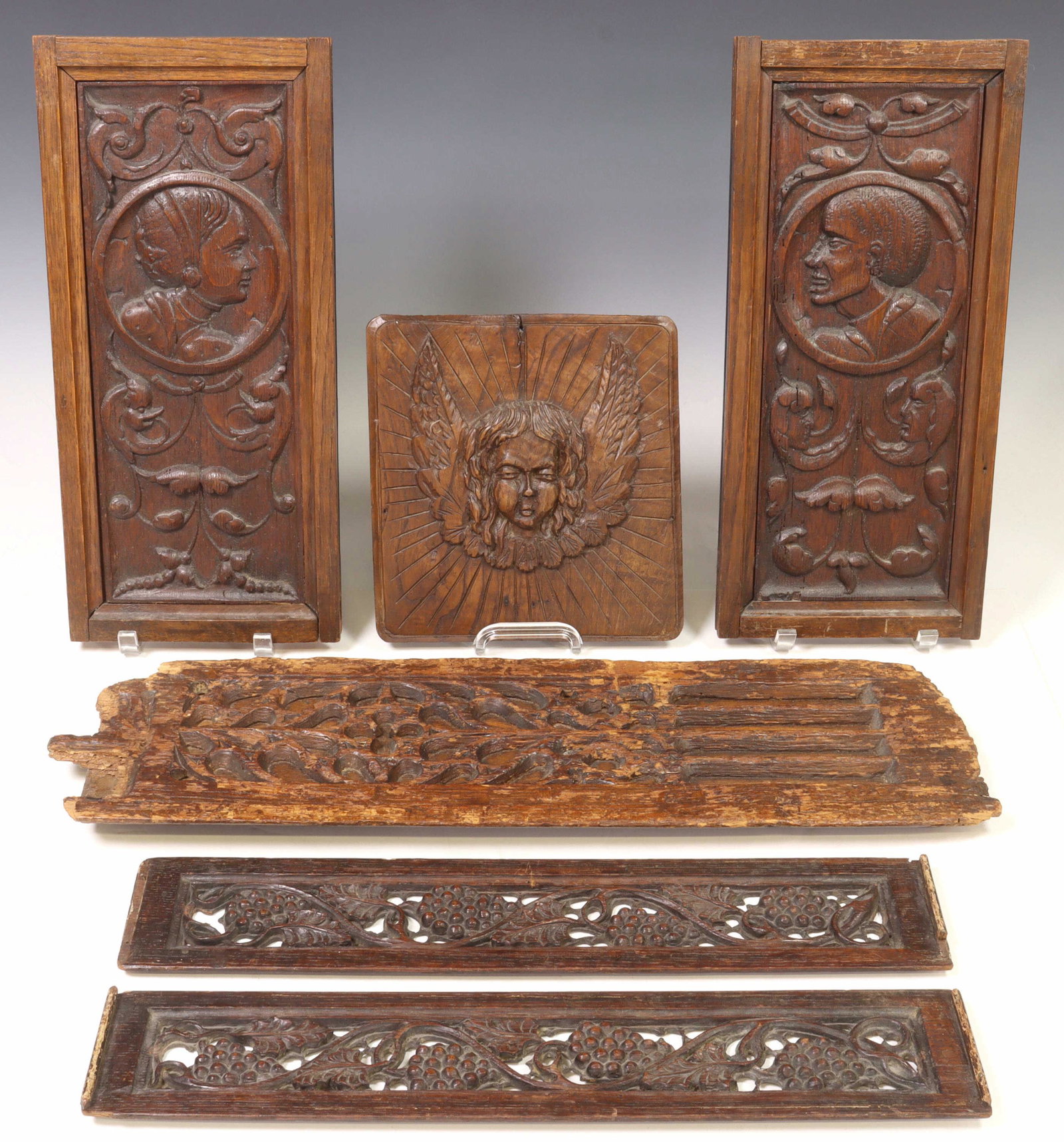 (6) CARVED OAK ARCHITECTURAL RELIEF WALL PANELS: (lot of 6) Carved oak architectural relief panels, late 19th c., including: (2) having portraits in profile, flanked by scrolled foliates, (2) with pierced grape vine carvings, (1) having central wing