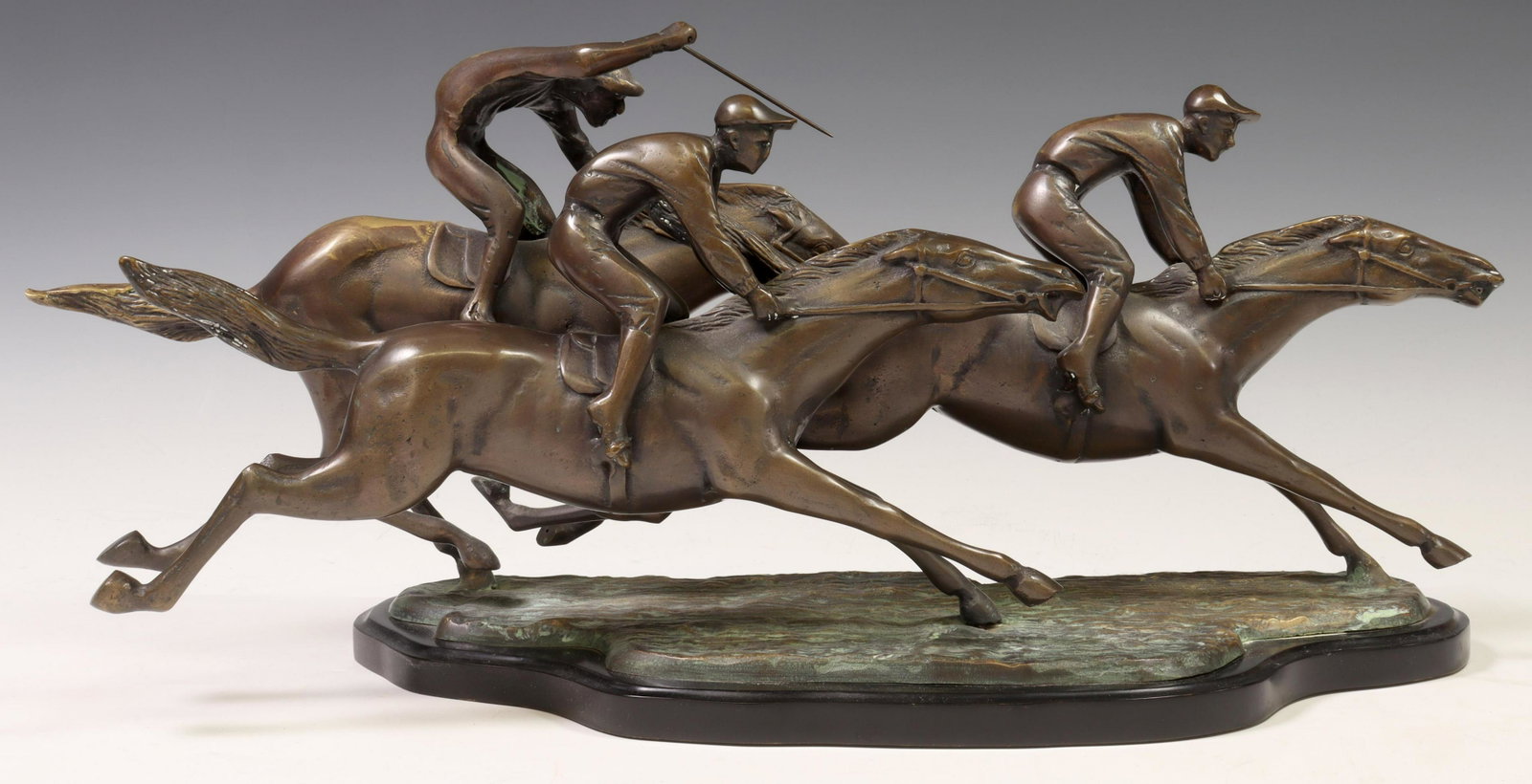 PATINATED BRONZE SCULPTURE, THREE HORSE JOCKEYS: Patinated bronze sculpture, Three Horse Jockeys, apparently unsigned, rising on verdigris and gilt bronze naturalistic base, further ending on black base, sculpture: approx 9.75"h, 24.25"w, 7"d, base: