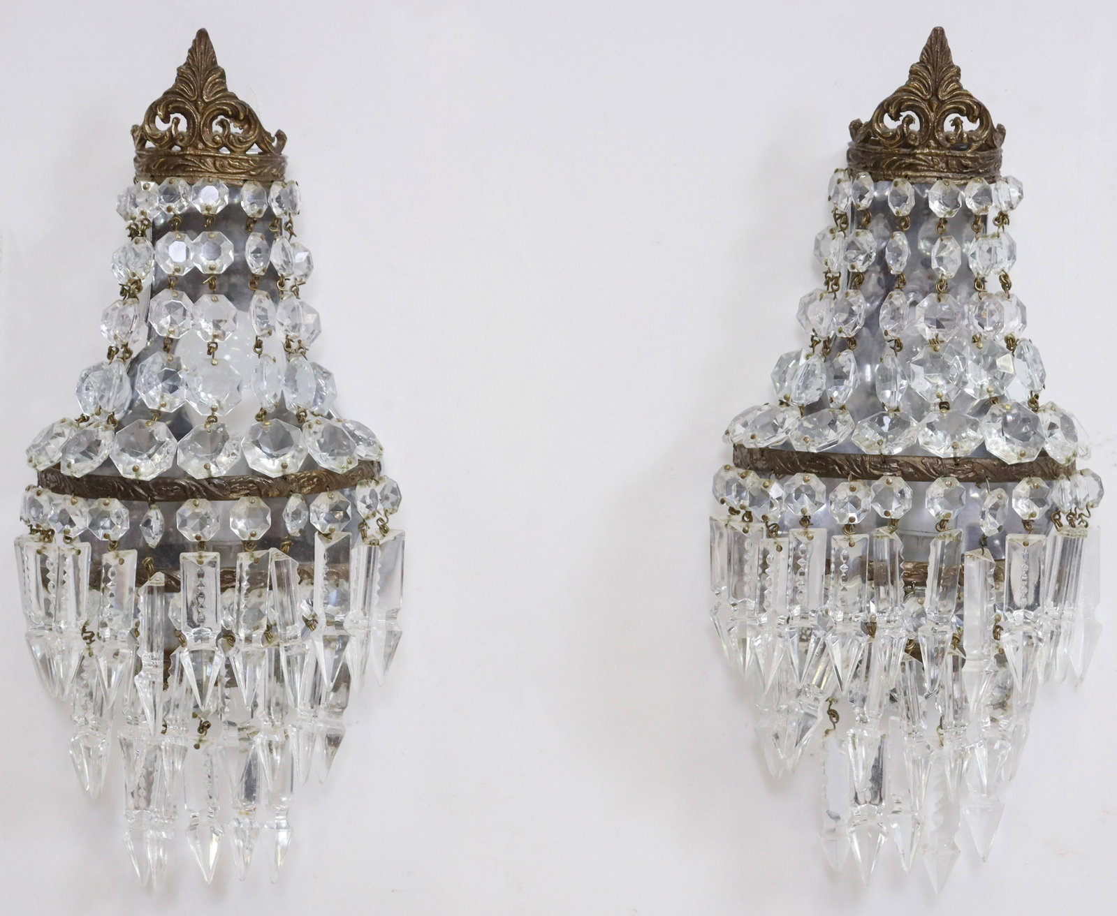 2) EMPIRE STYLE CRYSTAL PRISM 1-LIGHT WALL SCONCES: (pair) Empire style crystal prism single-light wall sconces, 20th c., gilt metal frame topped with foliate scroll crest, hung with tiers of drops and prisms, on reflective back plate, enclosing single