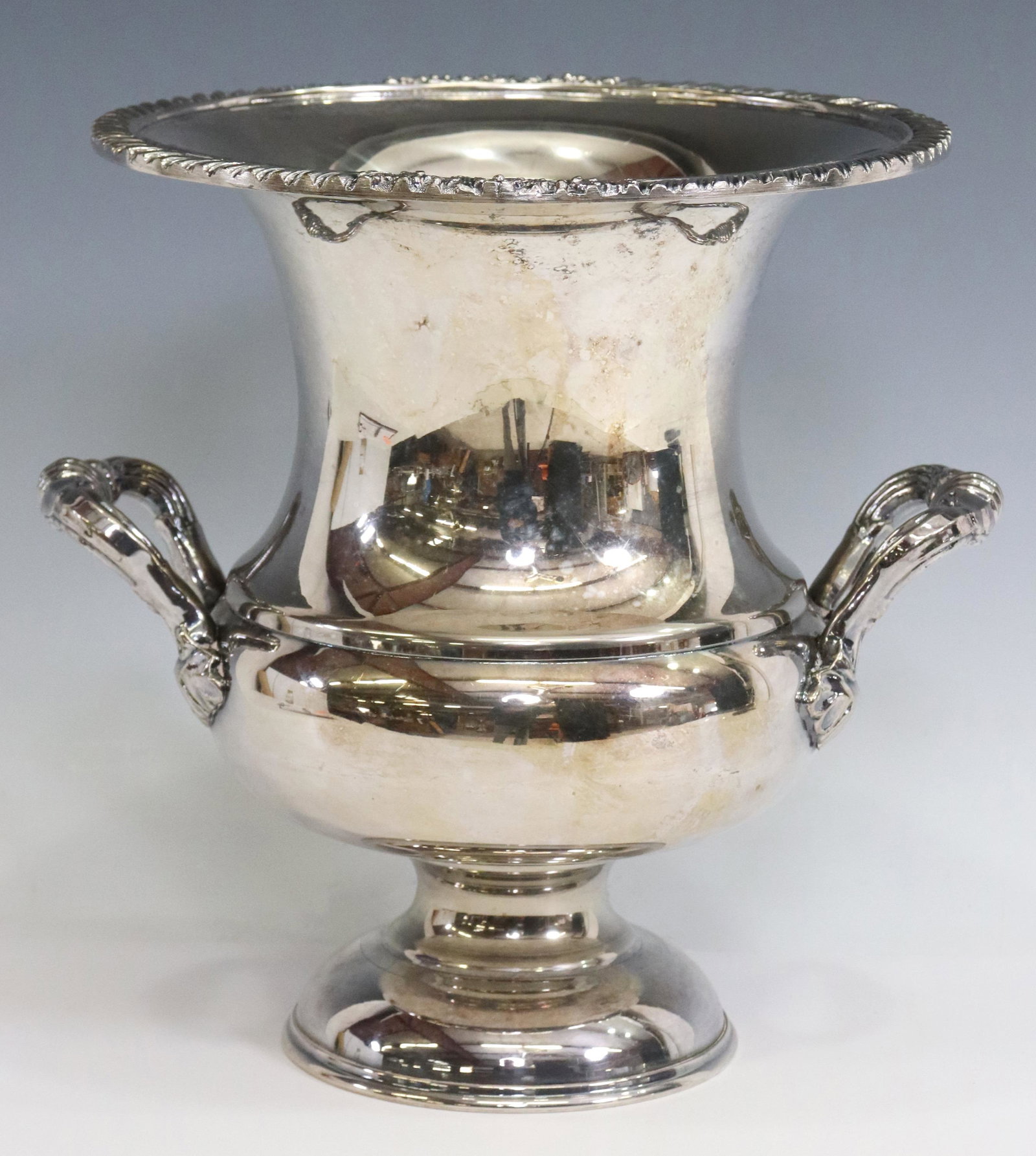 AMERICAN SILVERPLATE CHAMPAGNE BOTTLE COOLER: American silverplate champagne bottle cooler, English Silver Manufacturing Group, Brooklyn, New York, having repousse rim, over shell-accented handles, rising on round pedestal foot, approx 10 5/8"h, 