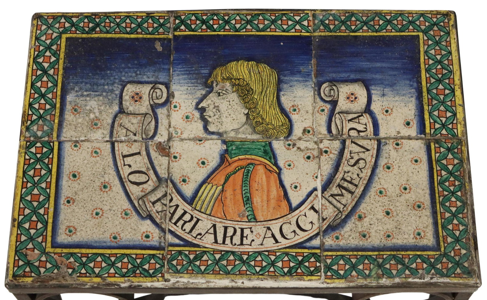 ITALIAN FIGURAL TILE-TOP IRON SIDE TABLE: Iron side table with tiled top, depicting portrait of a young man surrounded by the text 'A Lo Parlare Aggi Mesura", above scrolled frame, ending in square feet, approx 22.5"h, 19.25"w, 13"d**Provenan
