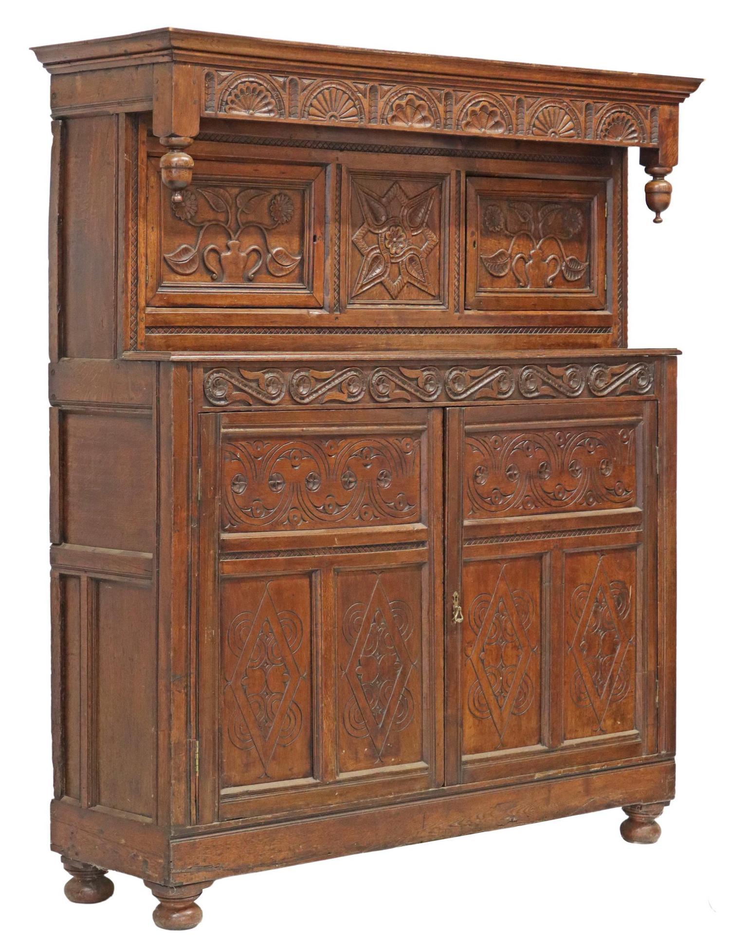 ENGLISH CARVED OAK COURT CUPBOARD: English oak court cupboard, 18th/ 19th c., molded cornice, lunette carved frieze, drop finials, two upper cabinet doors with floral carving, shallow work surface, lower case fitted with double-door ca