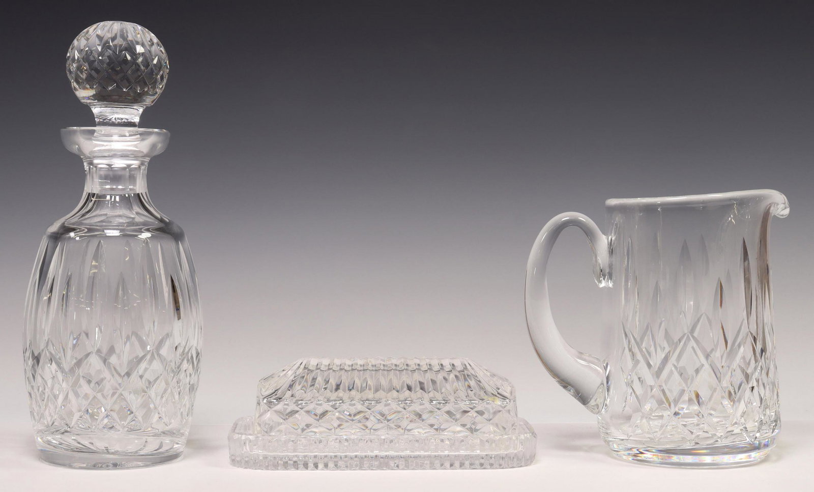 (3) WATERFORD BUTTER DISH LISMORE DECANTER PITCHER: (lot of 3) Waterford cut crystal tableware, including: (1) covered butter dish, approx 2.5"h, 7 3/8"l, 3 5/8"w, (1) "Lismore" pitcher, approx 6.5"h, (1) "Lismore" spirit decanter and multi-cut stopper