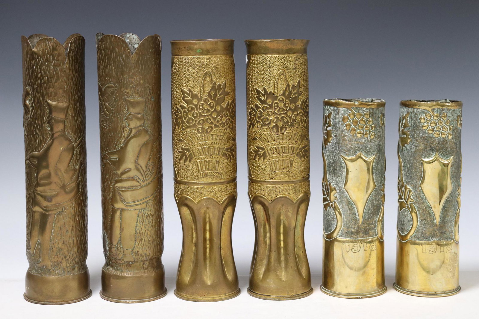 6) FRENCH WWI-ERA ARTILLERY SHELL TRENCH ART VASES: (lot of 6) French WWI-era trench art vases, fashioned from artillery shells, including: (2) with grapevine motifs and central shield, incised 1918, (2) with scalloped rim, figural motifs on a textured
