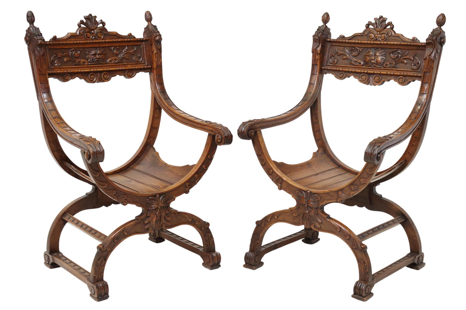 (2) FRENCH RENAISSANCE REVIVAL CURULE ARMCHAIRS: (pair) French Renaissance Revival carved walnut armchairs, 19th c., having foliate crest and finials, the whole carved with grotesque masks, scrolled handholds, rising on stretcher-joined curule base,