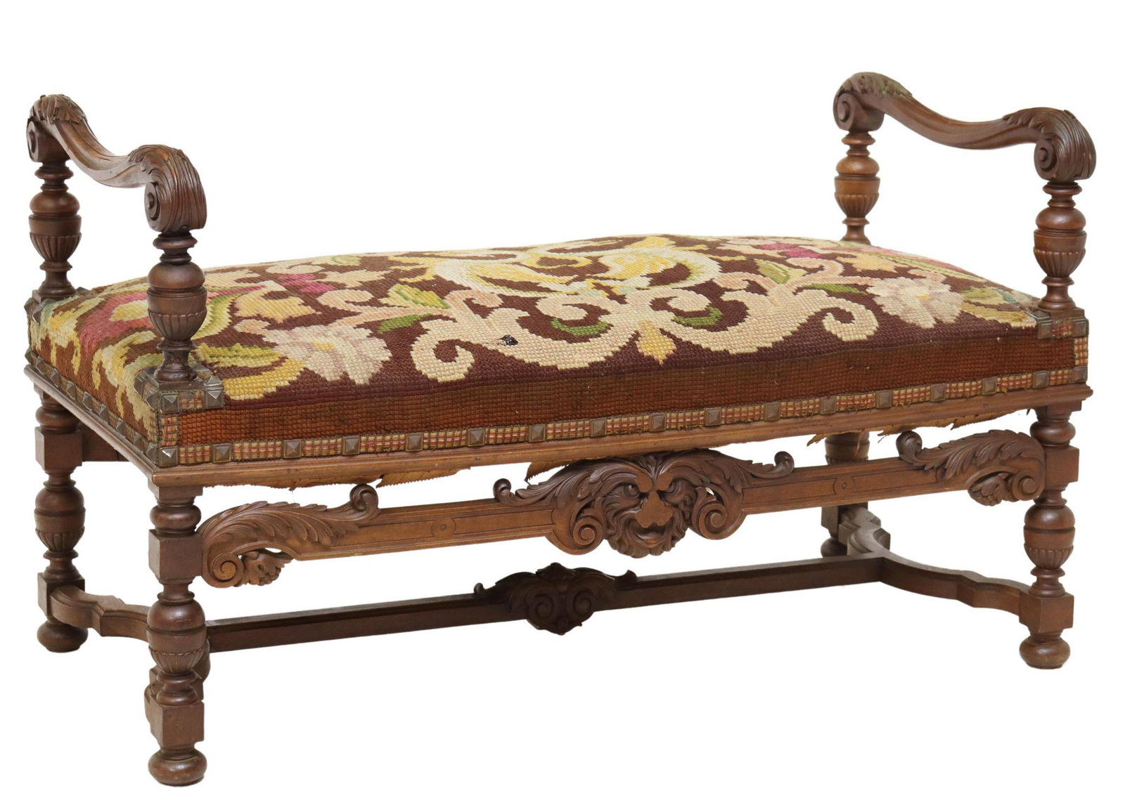 FRENCH RENAISSANCE REVIVAL CARVED WALNUT BENCH: French Renaissance Revival carved walnut end of bed bench, late 19th/ early 20th c., having scrolling foliate arm rails, seat in a needlepoint upholstery, over grotesque mask carved apron, rising on s