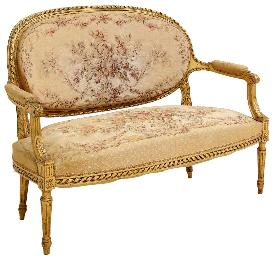 FRENCH LOUIS XVI STYLE GILTWOOD SETTEE, 19TH C.: French Louis XVI style giltwood sofa, late 19th c., having floral tapestry upholstery, padded arms, rising on tapered ribbed legs, approx 38"h, 51.5"w, 25"d, seat height: 18.5"h **Note: matching armch