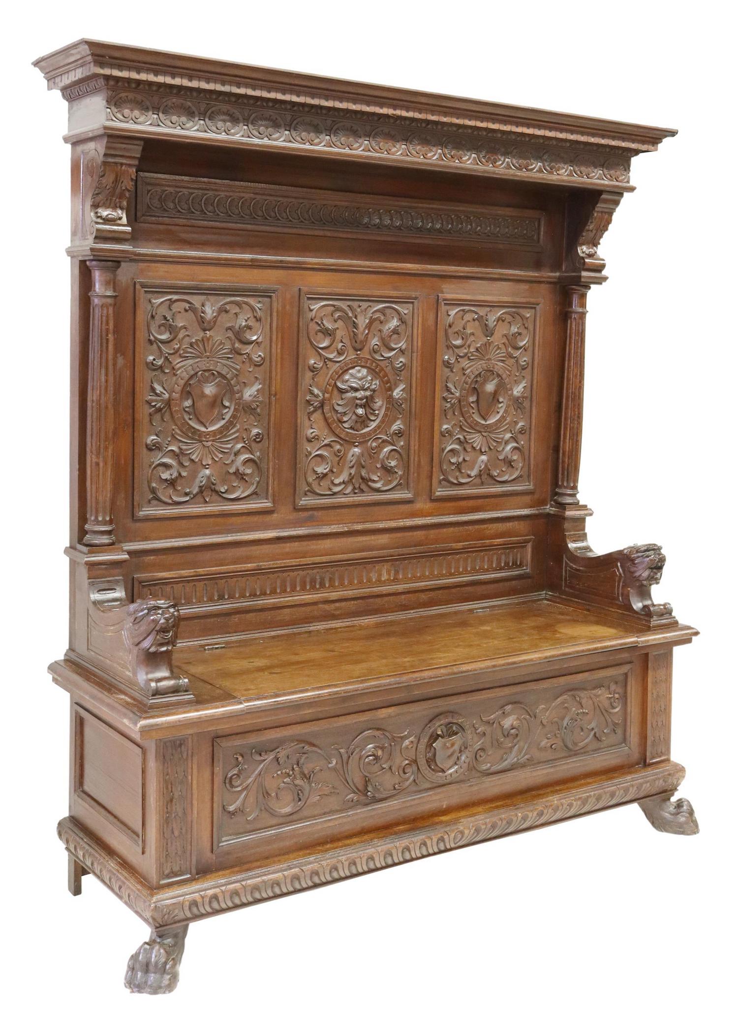 ITALIAN RENAISSANCE REVIVAL CARVED HALL BENCH: Italian Renaissance Revival walnut hall bench, Genova (Genoa), 19th c., having molded cornice, over foliate and grotesque carved back, lion hand holds, hinged seat, opening to storage interior, rising