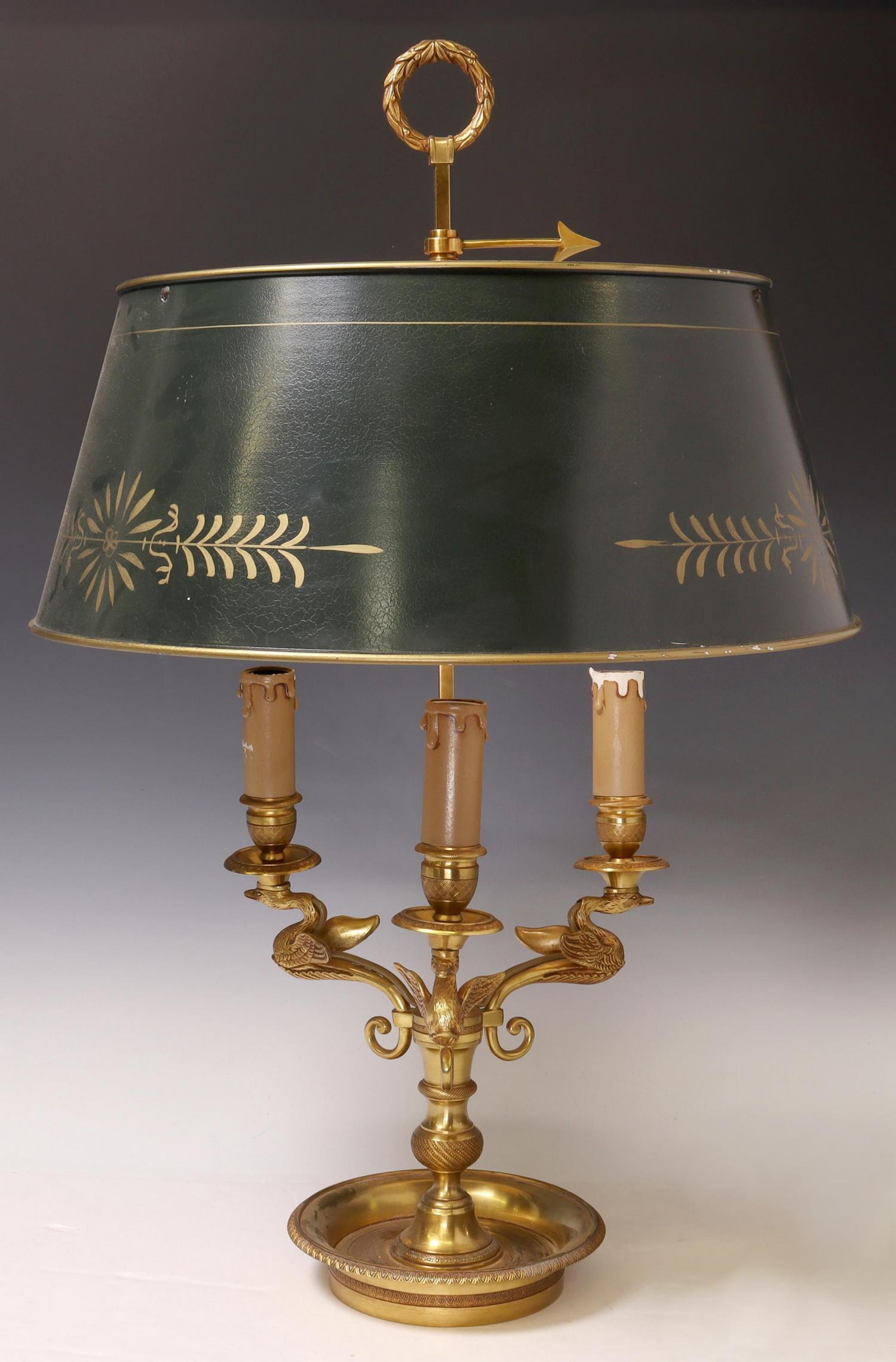 FRENCH EMPIRE STYLE BRONZE BOUILLOTTE TABLE LAMP: French Empire style bronze bouillotte table lamp, 20th c., having painted shade, over urn-form standard, issuing three swan arms, terminating in faux candle cups, rising on ornamented dish base, in ne