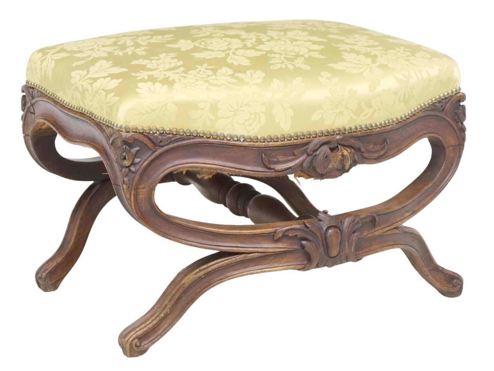 FRENCH LOUIS XV STYLE CARVED CURULE FOOTSTOOL: French Louis XV style footstool/ ottoman, 20th c., in a damask patterned upholstery, with nailhead trim, rising on foliate carved curule base, joined with center stretcher, ending on whorl feet, appro
