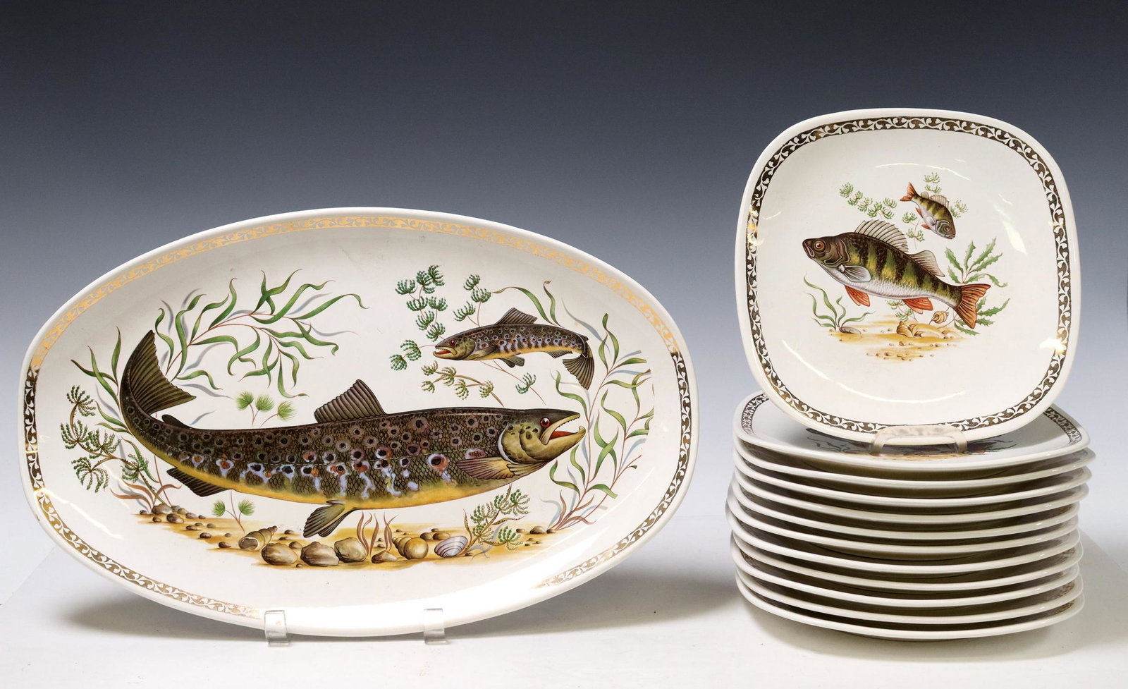 (13) FRENCH LONGCHAMP FAIENCE FISH SERVICE: (lot of 13) French faience fish service, Longchamp, including: (12) individual plates, with (six) unique transfer printed designs, (one) with small chip underfoot, approx 8.5"l, 8.5"w, (1) serving pla