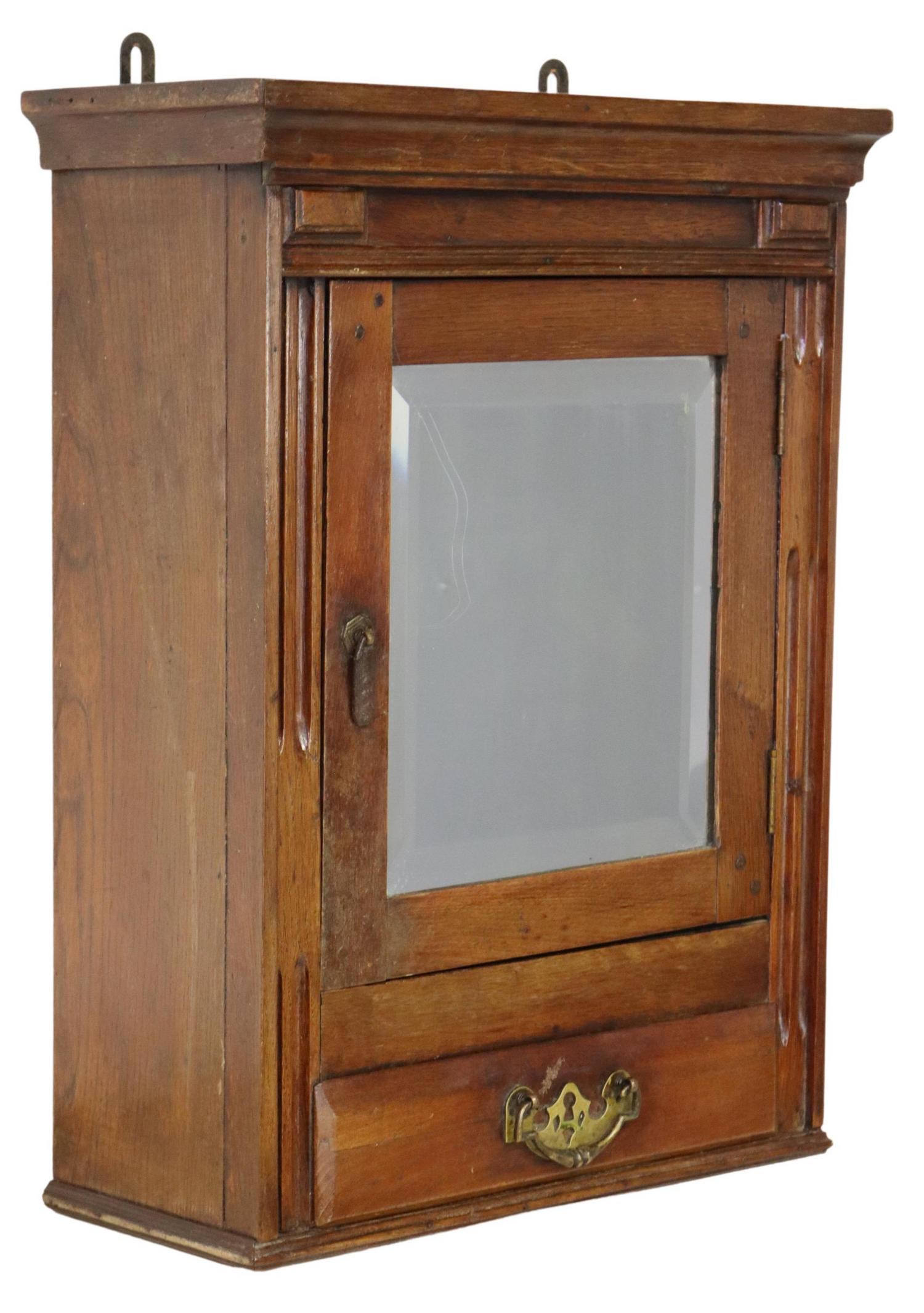 BEVELED MIRROR OAK WALL-MOUNTED CABINET: Oak wall-mounted wall / medicine cabinet, 20th c., having molded cornice, beveled mirror cabinet door, over single drawer, with batwing pull, approx 25"h, 18.75"w, 8.25"d Start Price: $100.00