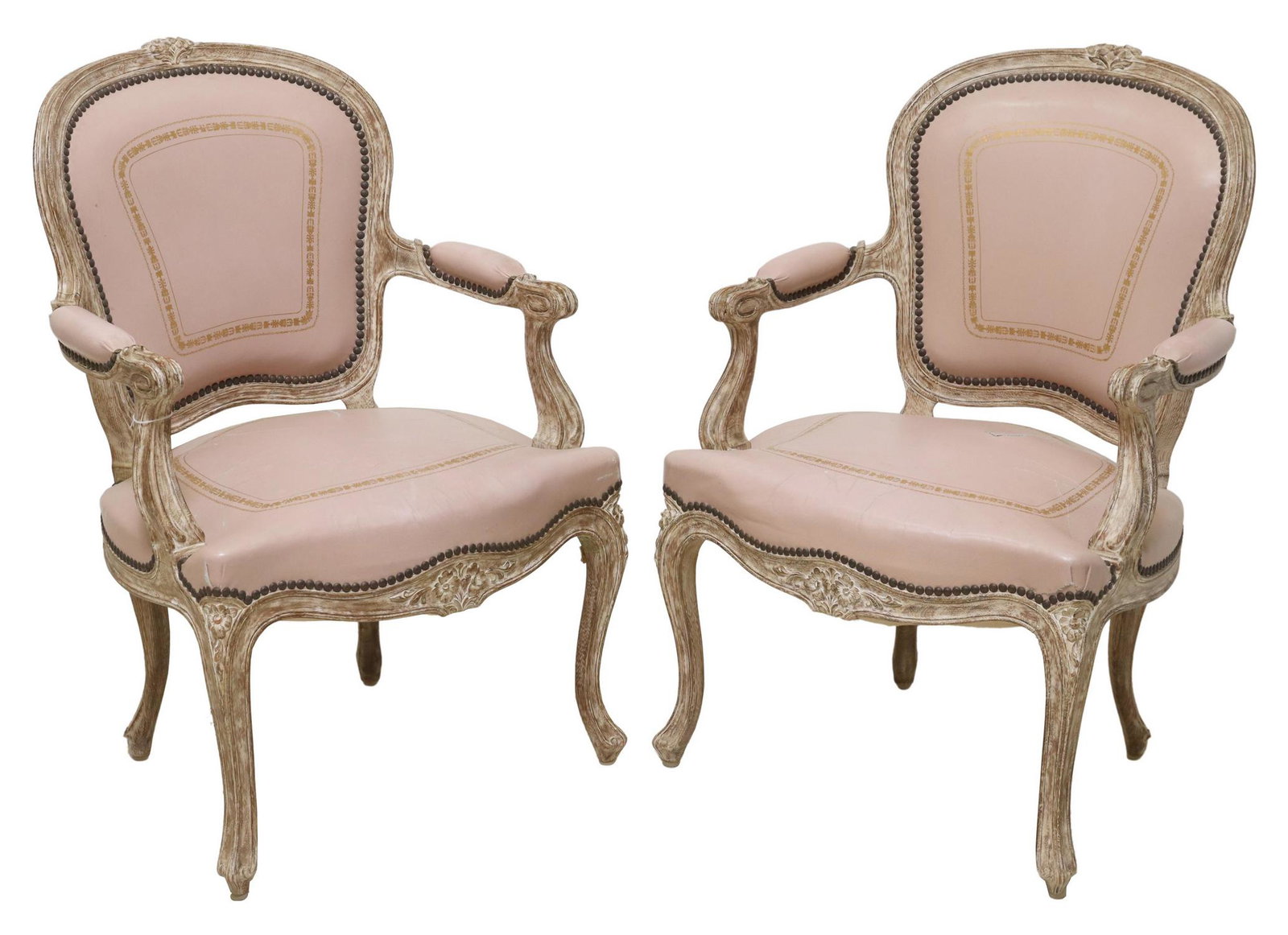 (2) FRENCH LOUIS XV STYLE LEATHER FAUTEUILS: (pair) French Louis XV style armchairs, 20th c., frame in an antiqued finish, having floral crest, worn pink leather upholstery, with nailhead trim, scrolled handholds, rising on cabriole legs, ending