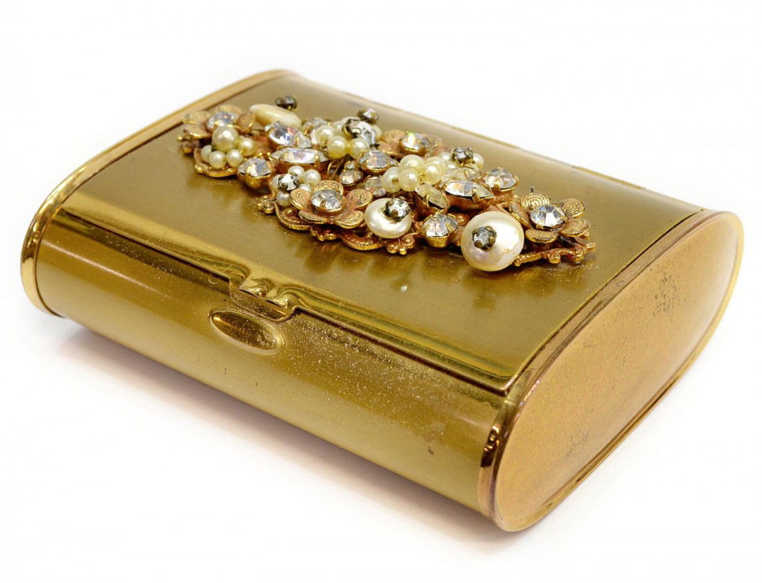 VINTAGE COMPACT, FLORAL DETAIL, POSSIBLY HASKELL: Vintage gilt metal compact, attributed by the consignor to Miriam Haskell, top embellishment showing a garden of flowers, wear/scratches to case, 3"l, 2.5"w, .25lb