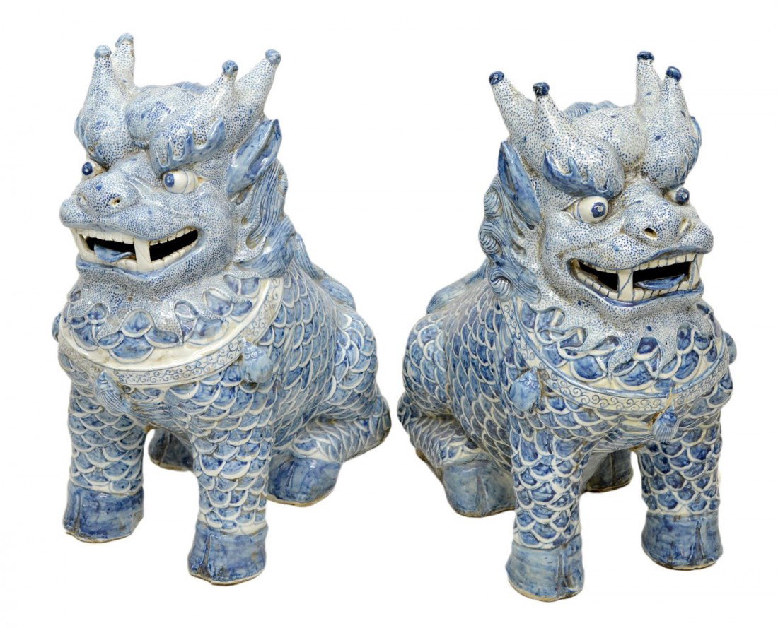 (PAIR) CHINESE BLUE & WHITE SEATED KILIN FIGURES: (pair) Large decorative Chinese ceramic Qilin figures, each the form of a lion like animal with speckled head, scaled body, bulging eyes, bearing teeth and tongue, hoofs, fire shaped antlers, long man