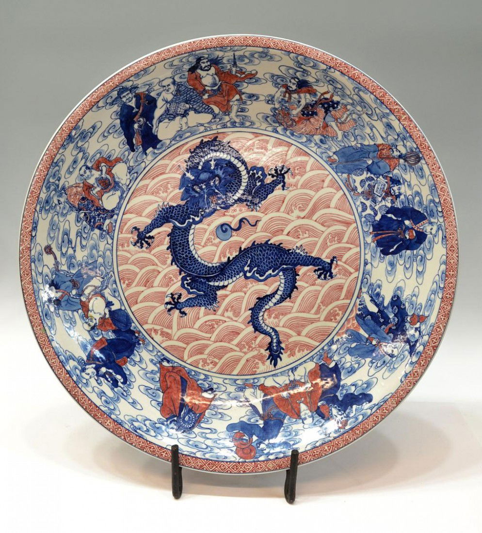 LARGE CHINESE RED & BLUE PAINTED PORCELAIN CHARGER: Large Chinese underglaze red and blue porcelain charger, a patterned red band enclosing a wide border decorated with celestial figures, the center showing a five-toed dragon and pearl in cobalt blue o
