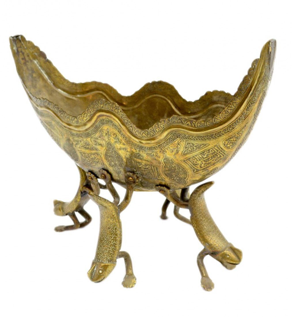 ISLAMIC BRASS BOAT FORM SERVICE DISH ON LEGS: Islamic brass serving dish, of boat shape with an undulating rim and decorated on the exterior with poetic phrases in elegant calligraphy amid animal and geometric motifs, all raised on four zoomorphi
