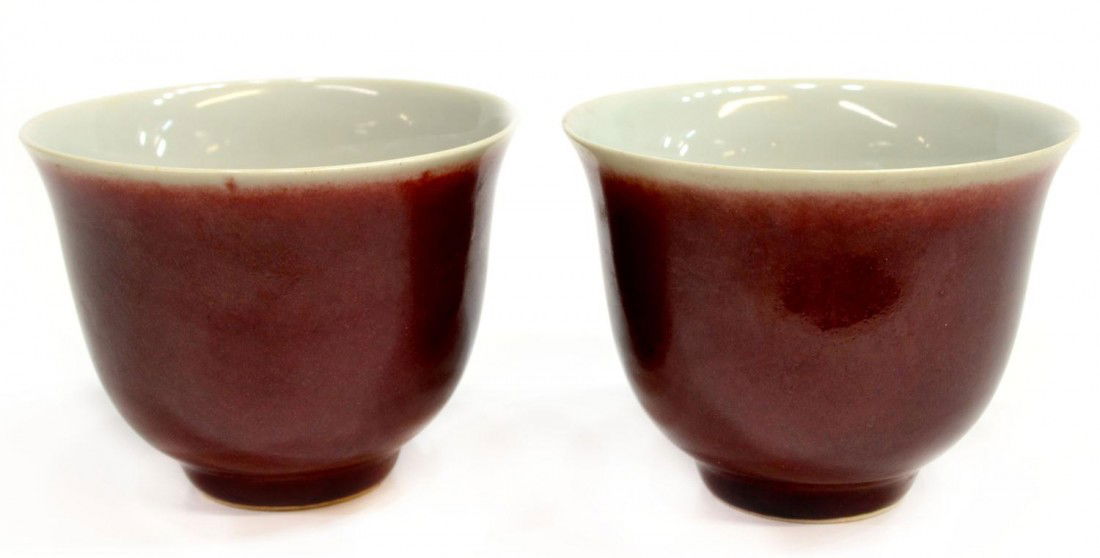 PAIR CHINESE LANG YAO GLAZED TEA CUPS: (pair) Chinese lang yao (sang de bouef) glazed tea cup, each of inverted bell shape with the exteriors covered in a rich red glaze continuing over the short ring foot, the glaze thinning to a pale gre