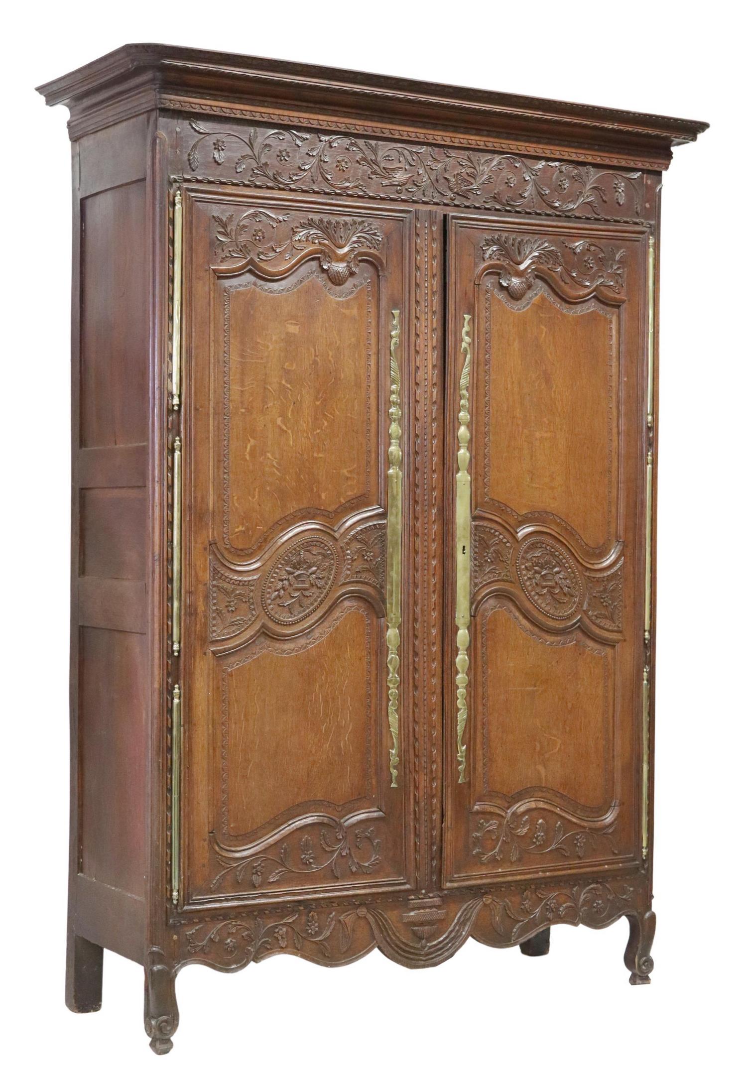 FRENCH PROVINCIAL LOUIS XV STYLE OAK ARMOIRE: French Provincial Louis XV style oak armoire, 19th c., the whole carved in foliates throughout, having molded cornice, dual doors, with gilt metal hardware, rising on cabriole legs, ending in whorl fe