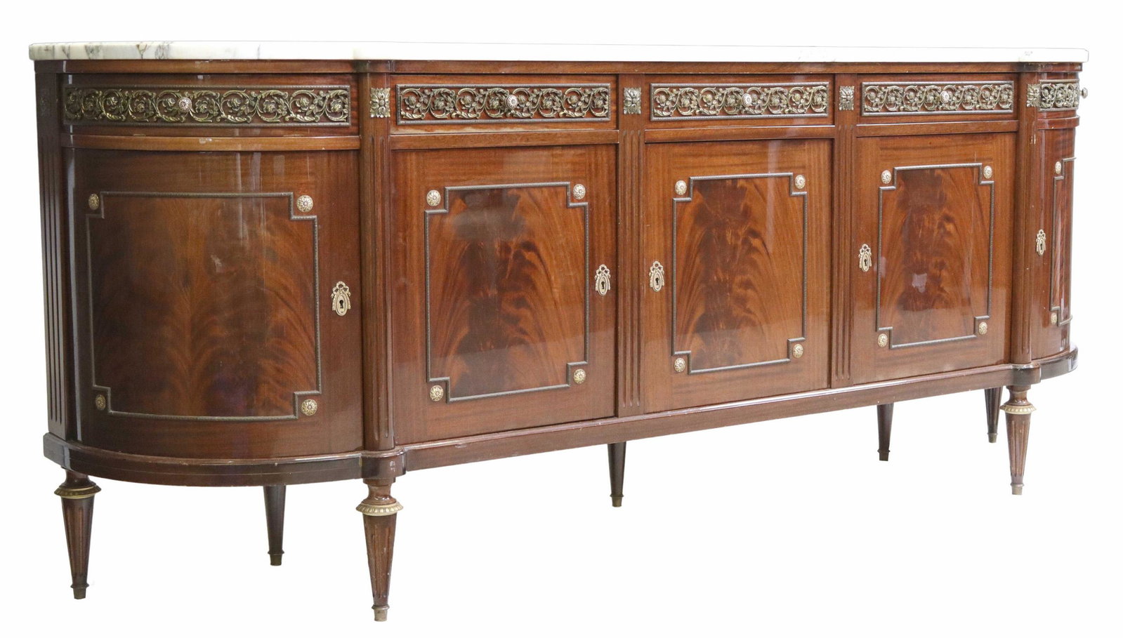 LOUIS XVI STYLE MARBLE-TOP MAHOGANY SIDEBOARD: Louis XVI style curved ends flame mahogany sideboard, 20th c., having a marble top over five drawers above five doors, brass ormolu and ribbed half columns accents, rising on tapered legs, approx. 39.