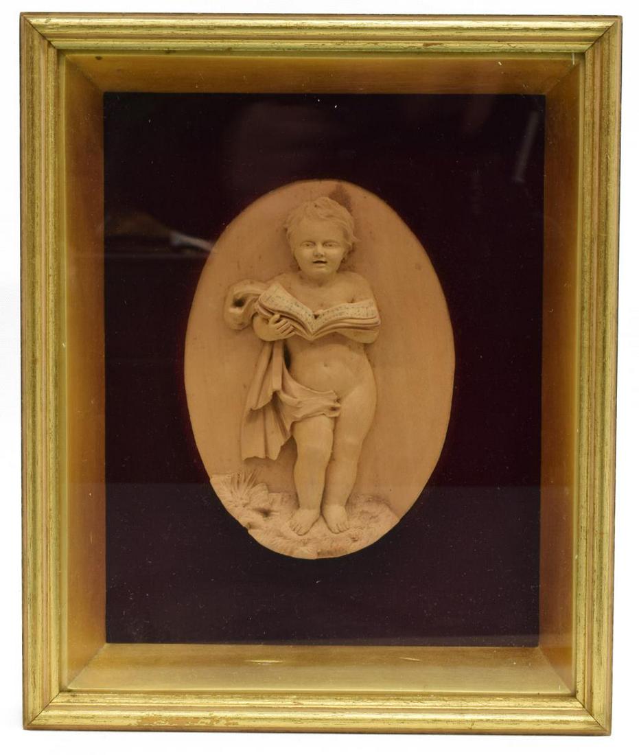 FRAMED CARVED WOOD PLAQUE SINGING PUTTO: Framed carved wood plaque, depicting a singing putto in high relief, with draped cloth, reading from a book of sheet music, overall: approx 9.25"h, 7.5"w, 1.5lbs Start Price: $50.00