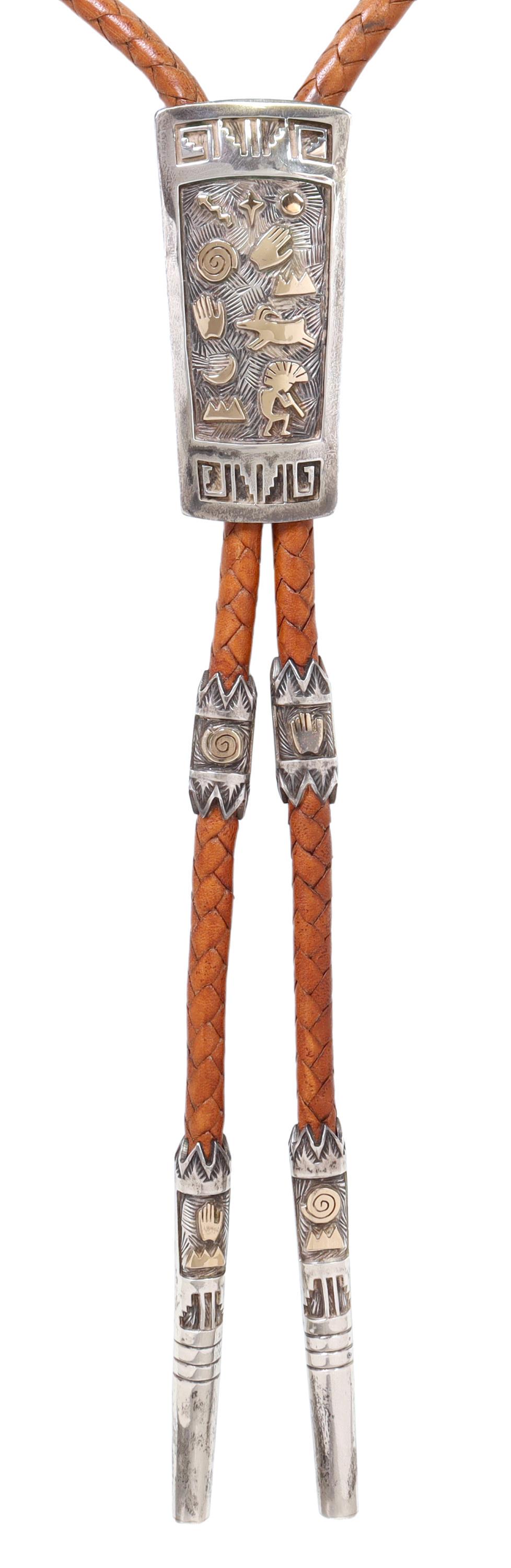 ARLAND F. BEND NAVAJO 14K & STERLING BOLO TIE: Native American sterling silver bolo tie with 14kt yellow gold applique, Arland F. Ben (Navajo, b.1962), large ornament with petroglyph symbols, silver overlay designs, matching sleeves and bolo tips,