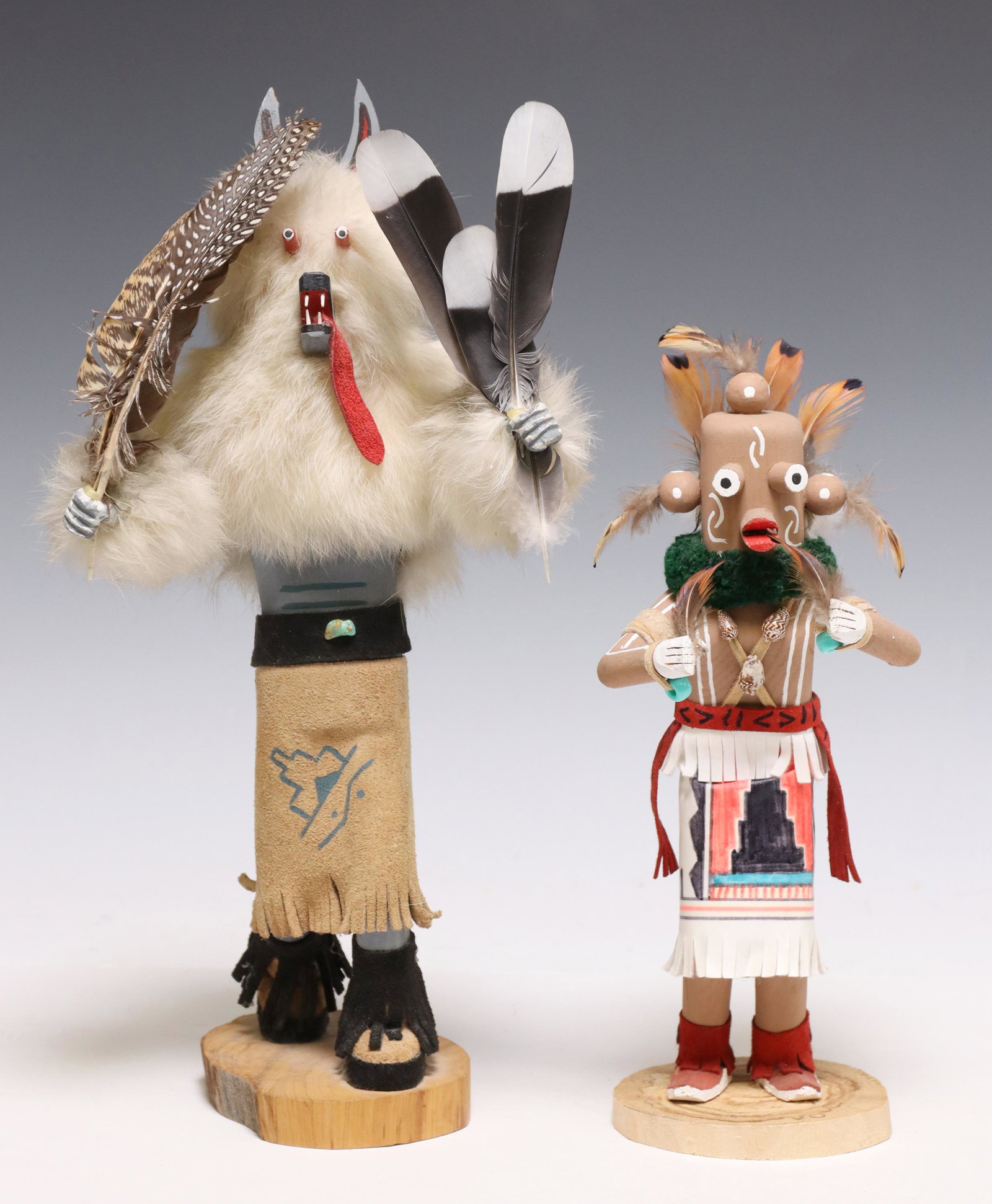 (2) NATIVE AMERICAN MUDHEAD & WOLF KACHINA DOLLS: (lot of 2) Native American carved Kachina dolls, both polychrome painted and embellished with leather, fur, and feathers, rising on wood slice base, including: (1) Mudhead Kachina, signed underfoot wi