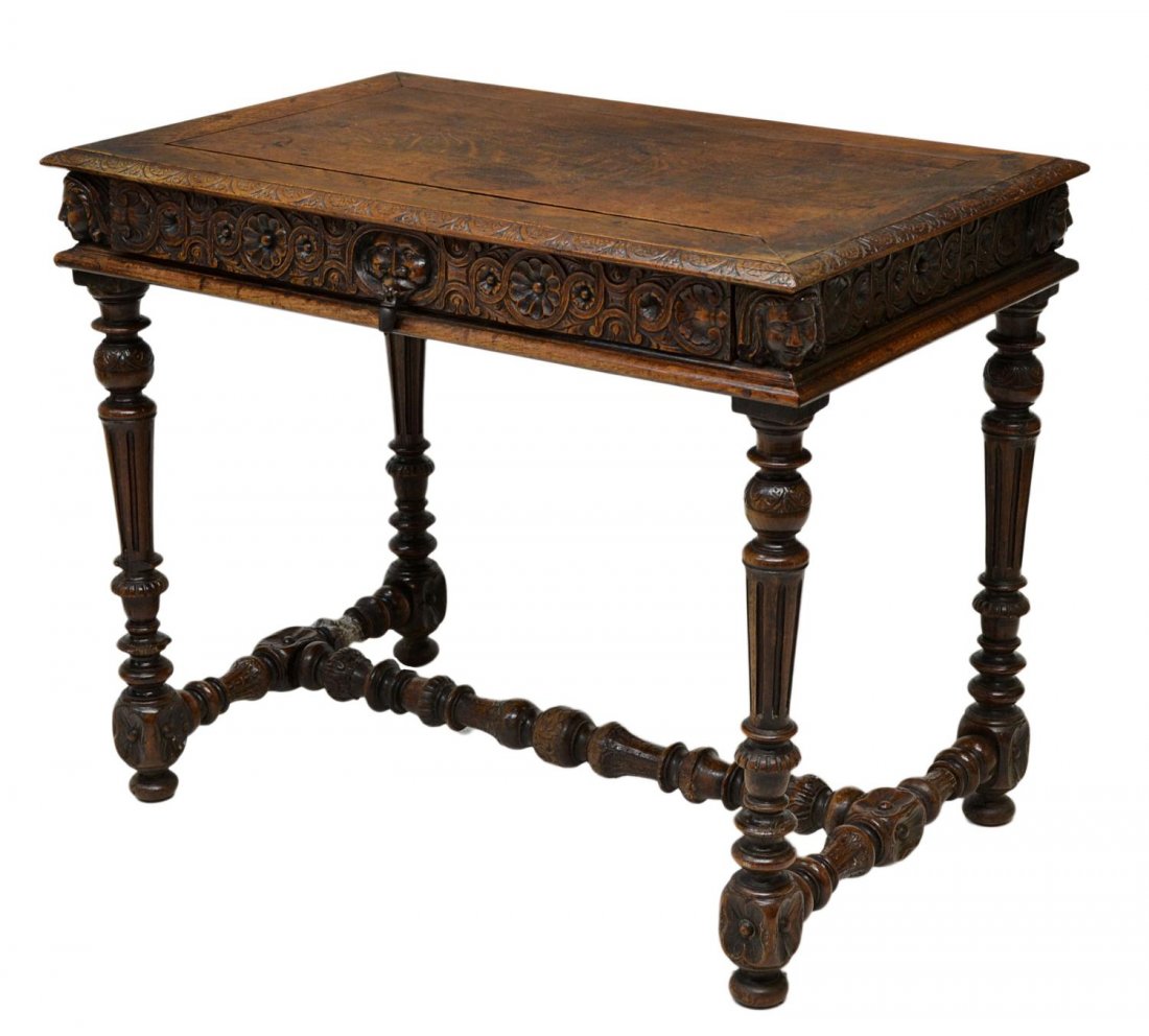 ANTIQUE ITALIAN RENAISSANCE CARVED WRITING TABLE: Italian Renaissance style carved oak writing table, 19th c., the rectangular top having carved edges, above a single frieze drawers, carved masks at each corner, rising on fluted legs terminating with