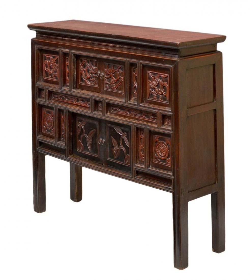 ASIAN CARVED RED & BLACK LACQUER CABINET: Asian lacquered red and black cabinet, the rectangular top surmounting the slightly tapered case set with foliate carved panels, two sliding doors open to storage, raised on four tall legs, 39.5"h, 40