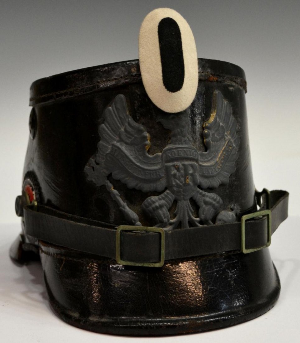 GERMAN SHAKO HELMET, PRUSSIA: German shako helmet fitted with gray over bright brass metal front plate depicting the Prussian coat of arms, polished leather body, neck guard with sewn thread separated, chin strap, one side with re