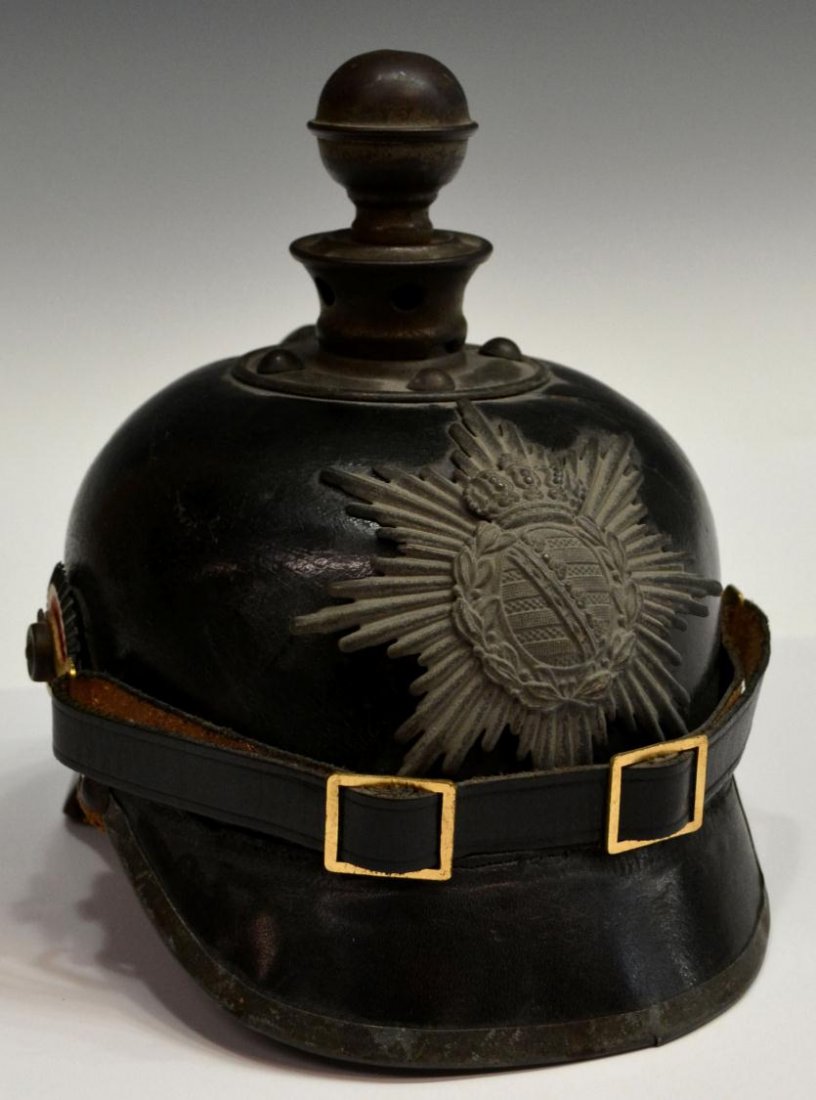 GERMAN PICKELHAUBE BALL HELMET, ARTILLERY, SAXONY: German pickelhaube artillery helmet fitted with metal front plate depicting the Saxony coat of arms, leather body, metal rim at visor with break, plain neck guard with loss of leather, later chin stra