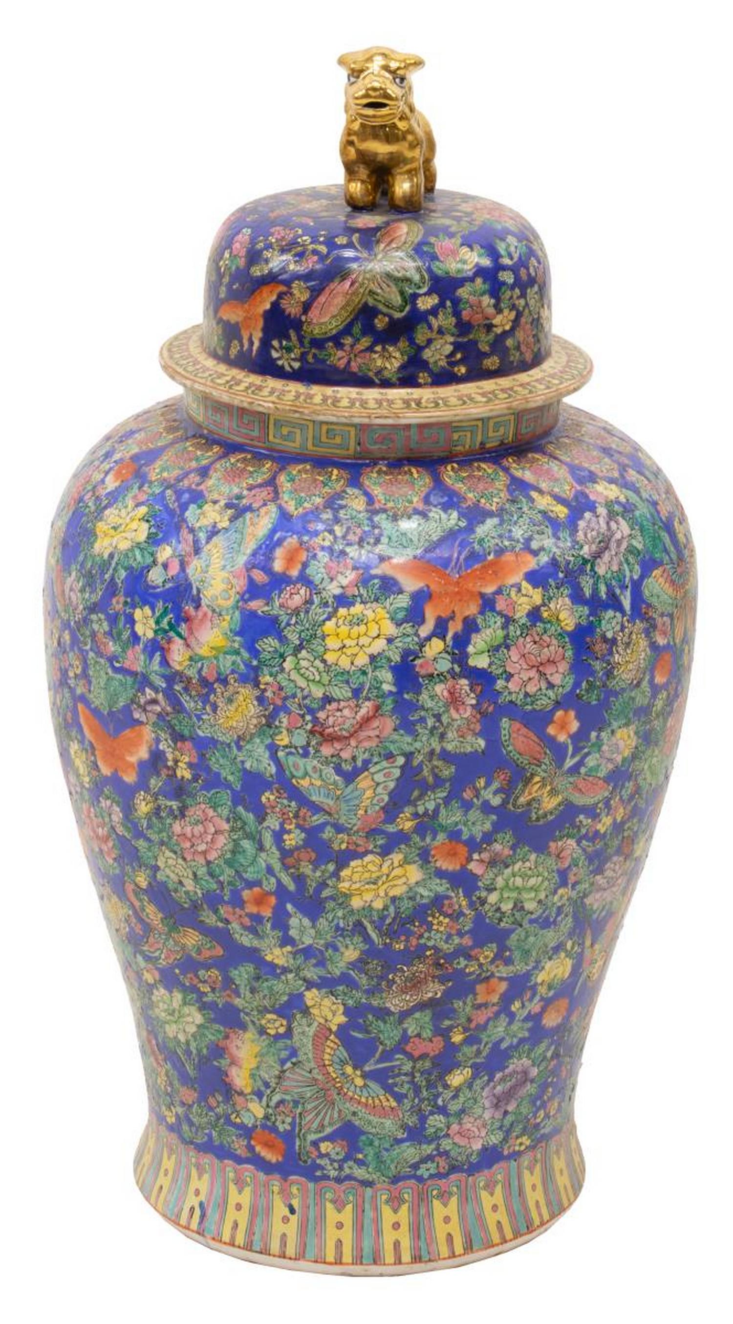 CHINESE PORCELAIN TEMPLE JAR WITH BUTTERFLIES: Large Chinese parcel gilt famille rose enameled porcelain temple jar, the domed cover surmounted by a foo lion, bright blue ground profusely decorated with blooming flowers and butterflies, honorific 