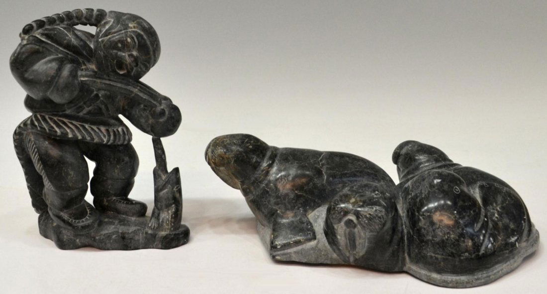 INUIT STONE CARVINGS, WALRUS & FISHERMAN, ADAMIE: (lot of 2) Inuit stone sculptures: (1) carved as a figure ice fishing, signed twice Adamie, one being crossed through, other marks as pictured, numbered 112486, 7.5"h; (1) large group carved as four w