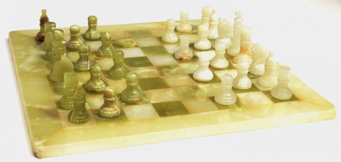 A CARVED ALABASTER CHESS SET IN CARRYING CASE: (set) Carved green and white alabaster chess set comprised of (32) playing pieces and matching alabaster chess board, red faux velvet carrying case, some chipping and age, largest: 3"h, smallest: 1"h,