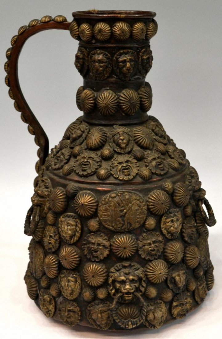 LARGE ANTIQUE COPPER JUG APPLIED LION MASKS: Large antique copper jug completely applied with gilt metal figural masks, ribbed metal ovals and lower front medallion with Egyptian motif, dent underfoot, 15"h, 10"w, 14.25lbs **Provenance: the esta