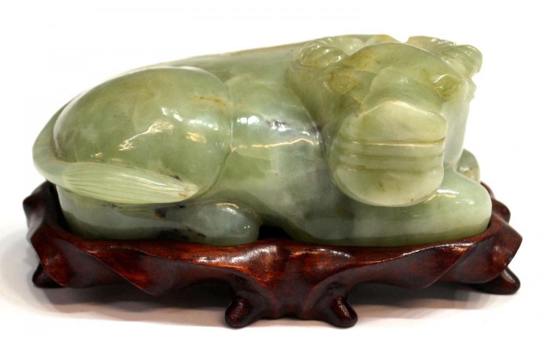CHINESE CARVED JADE FIGURE OF AN OX: Chinese light celadon jade carving of an ox, naturally occurring fissures, on wood base, 2"h,5"w,3"d, with stand: 2.75"h, 1.25lbs **Provenance: From the private collection of a Colonel (ret.) in the U