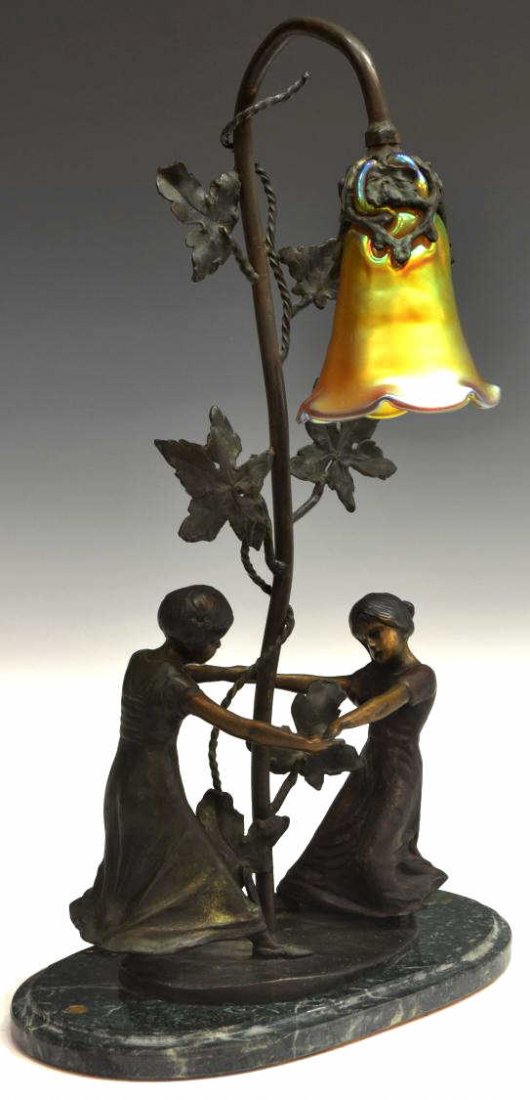 VINTAGE PATINATED BRONZE & ART GLASS FIGURAL LAMP: Vintage patinated bronze figural lamp, a pair of children join hands at the base of the foliated standard terminating in a uniquely fitted gold iridescent glass shade, in the style of Auguste Moreau (