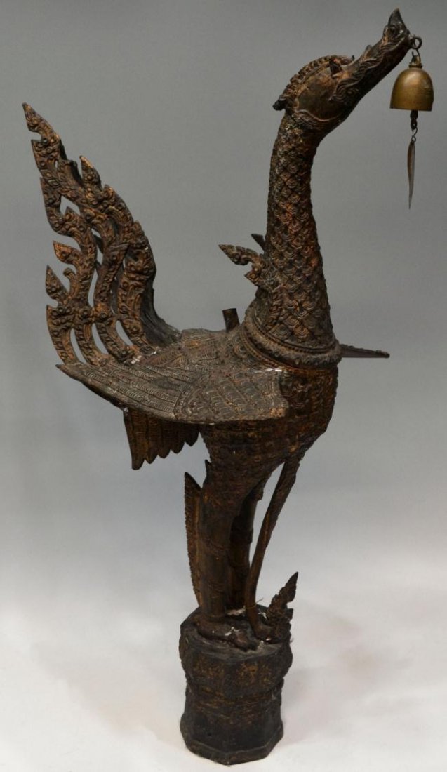 THAI SUPANNAHONG BRONZE BIRD SCULPTURE, 36"H: Buddhist Supannahong (various spellings) bird sculpture, Northern Thailand, early 20th c., a bronze form on integral circular stand, the bird, with wings extended, holds a bell in its beak, 36"h, 15"w